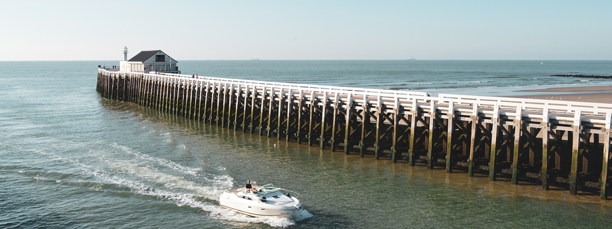 Jetty with boat in Blankenberge sea and beach